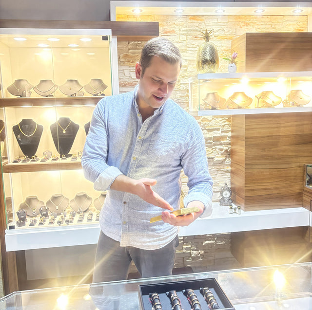 Mann hält Goldbarren in der Hand