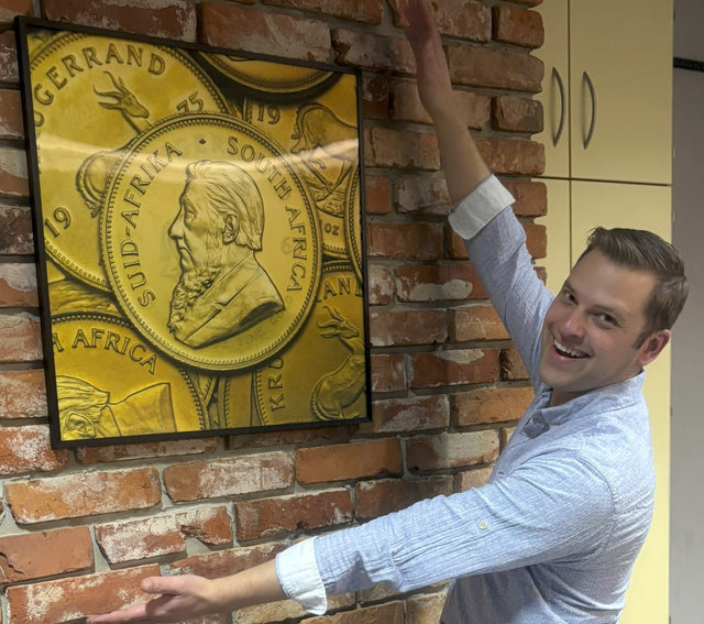 Mann präsentiert aufgehangenes Bild einer Goldmünze