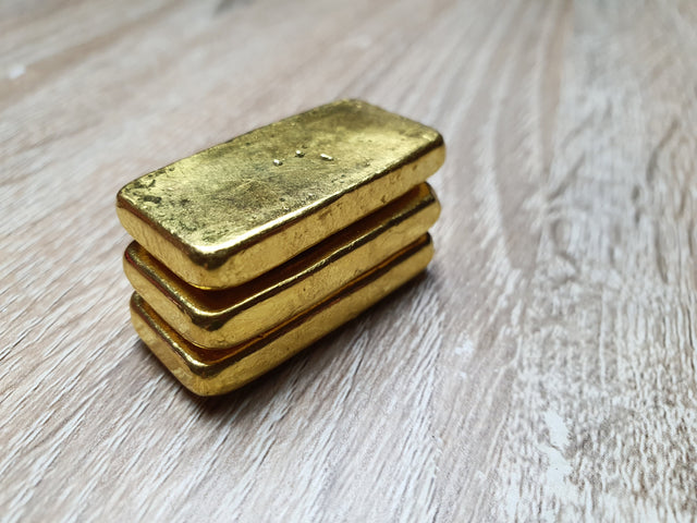 Drei Goldbarren gestapelt auf Tisch