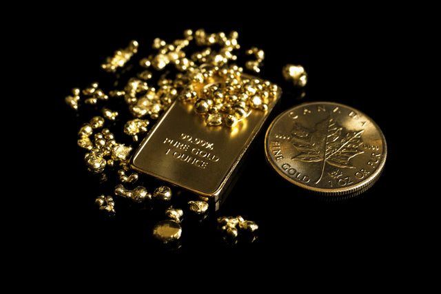 Goldbarren, Goldmünze und Goldnuggets vor schwarzem Hintergrund